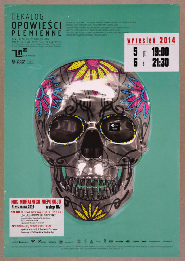 Polski plakat teatralny do spektakl u"Dekalog: Opowieści Plemienne". Duża stylizowana czaszka z kolorowymi wzorami.