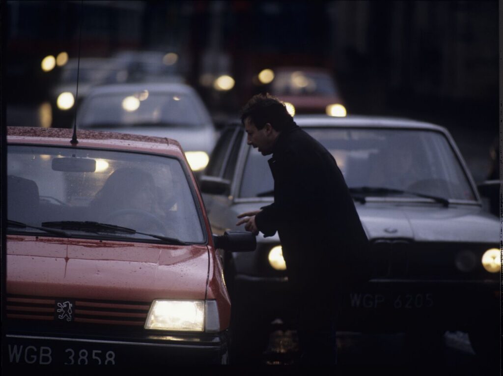 Karol (Zbigniew Zamachowski) stops a car with "Blondynka" (Grażyna Szapołowska) driving down the street.