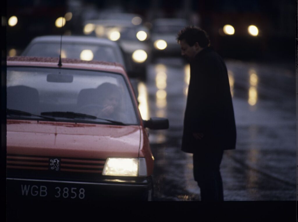 Karol (Zbigniew Zamachowski) stops a car with "Blondynka" (Grażyna Szapołowska) driving down the street.