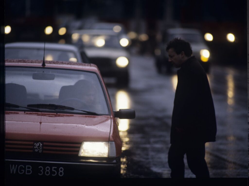 Karol (Zbigniew Zamachowski) stops a car with "Blondynka" (Grażyna Szapołowska) driving down the street.