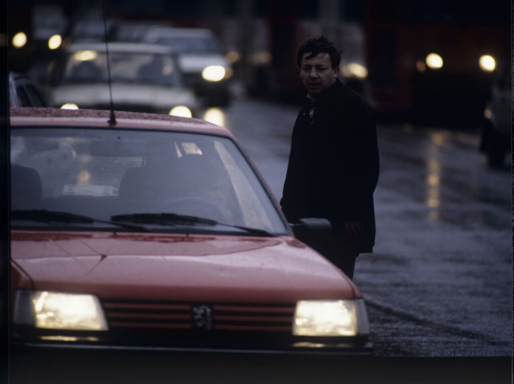 Karol (Zbigniew Zamachowski) stops a car with "Blondynka" (Grażyna Szapołowska) driving down the street.