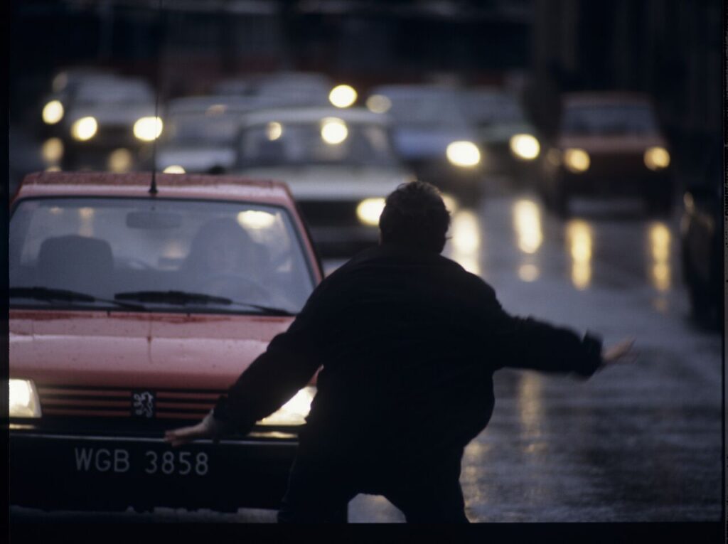 Karol (Zbigniew Zamachowski) stops a car with "Blondynka" (Grażyna Szapołowska) driving down the street.