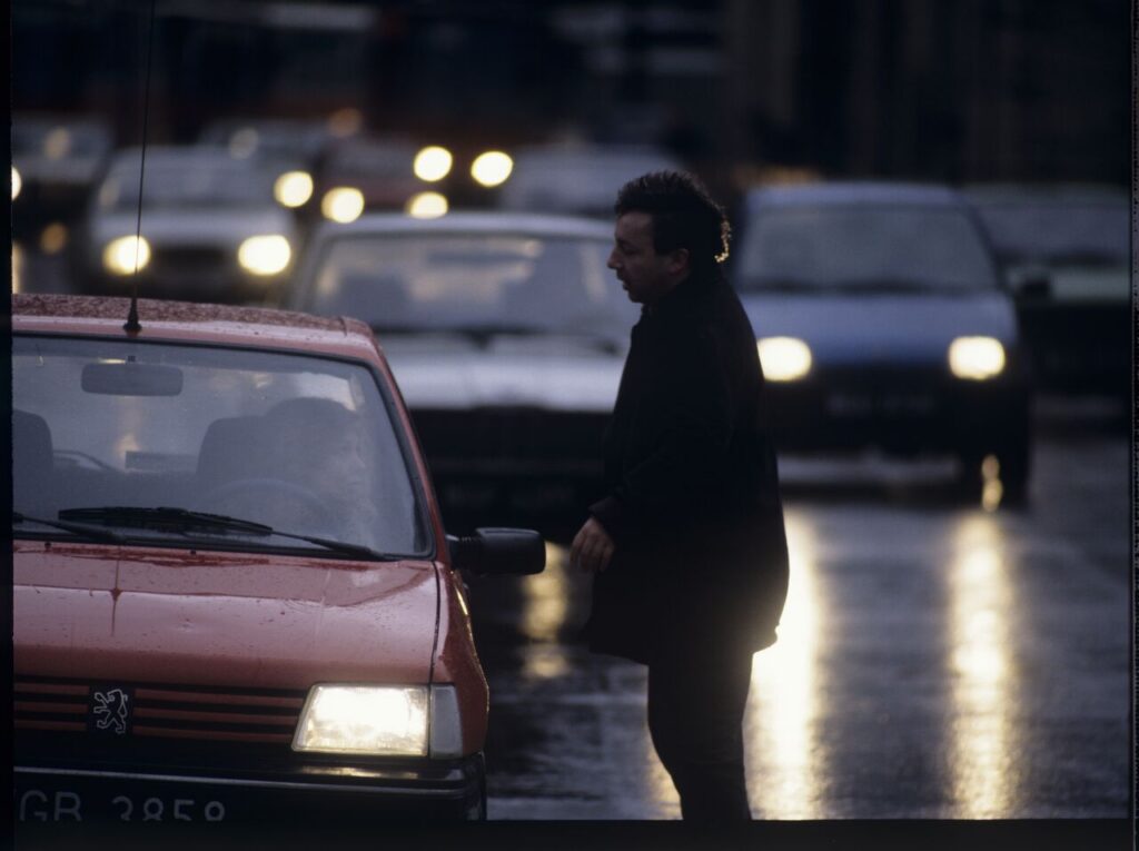 Karol (Zbigniew Zamachowski) stops a car with "Blondynka" (Grażyna Szapołowska) driving down the street.