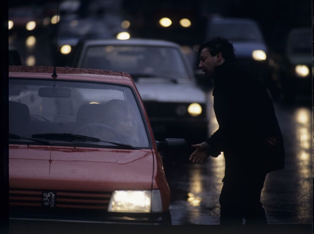 Karol (Zbigniew Zamachowski) stops a car with "Blondynka" (Grażyna Szapołowska) driving down the street.