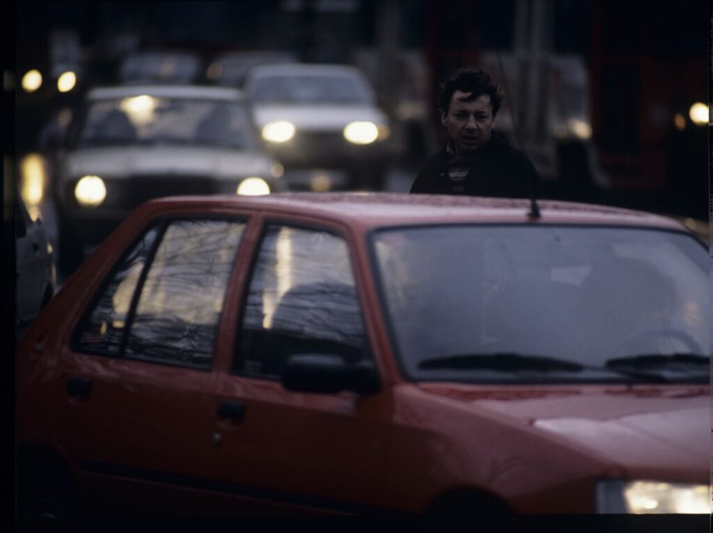 Karol (Zbigniew Zamachowski) stops a car with "Blondynka" (Grażyna Szapołowska) driving down the street.