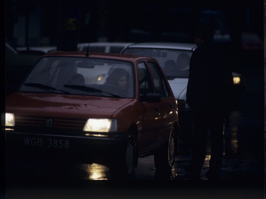 Karol (Zbigniew Zamachowski) stops a car with "Blondynka" (Grażyna Szapołowska) driving down the street.