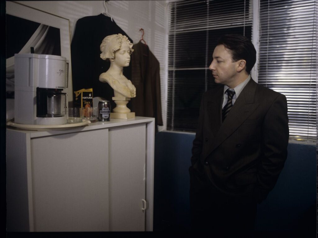 Karol (Zbigniew Zamachowski) as a businessman in his office with a plaster bust of a woman.