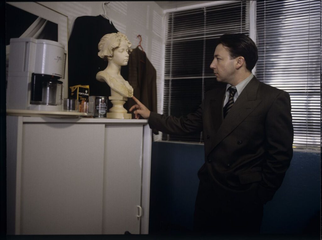 Karol (Zbigniew Zamachowski) as a businessman in his office with a plaster bust of a woman.