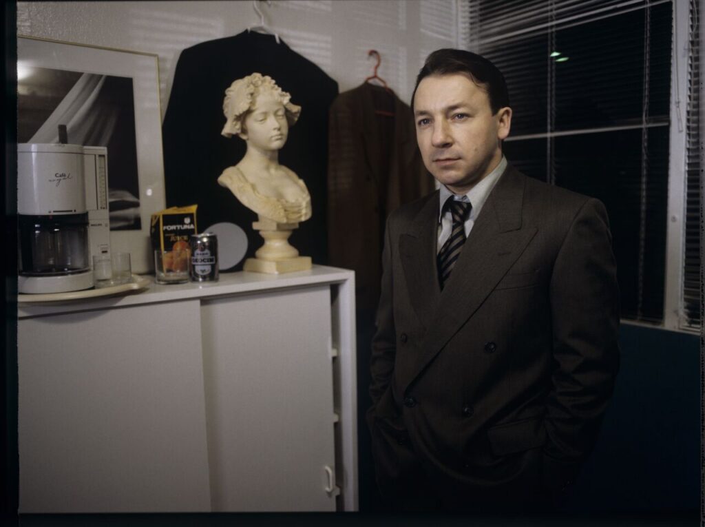 Karol (Zbigniew Zamachowski) as a businessman in his office with a plaster bust of a woman.