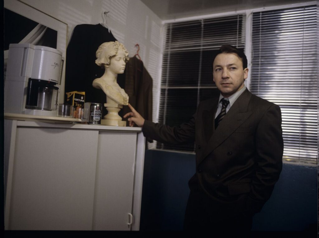 Karol (Zbigniew Zamachowski) as a businessman in his office with a plaster bust of a woman.
