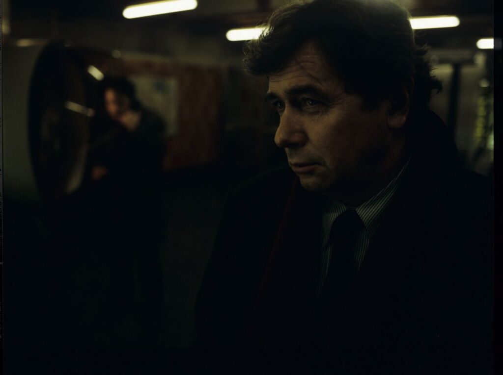 Mikołaj (Janusz Gajos) by the Paris metro. In the background Karol (Zbigniew Zamachowski) calls his wife Dominique.