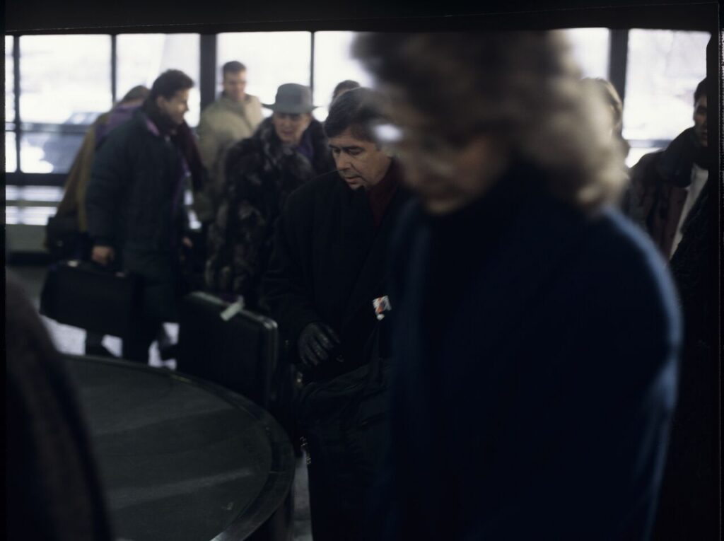 Mikołaj (Janusz Gajos) is waiting for his luggage in the arrivals hall at the Warsaw airport.