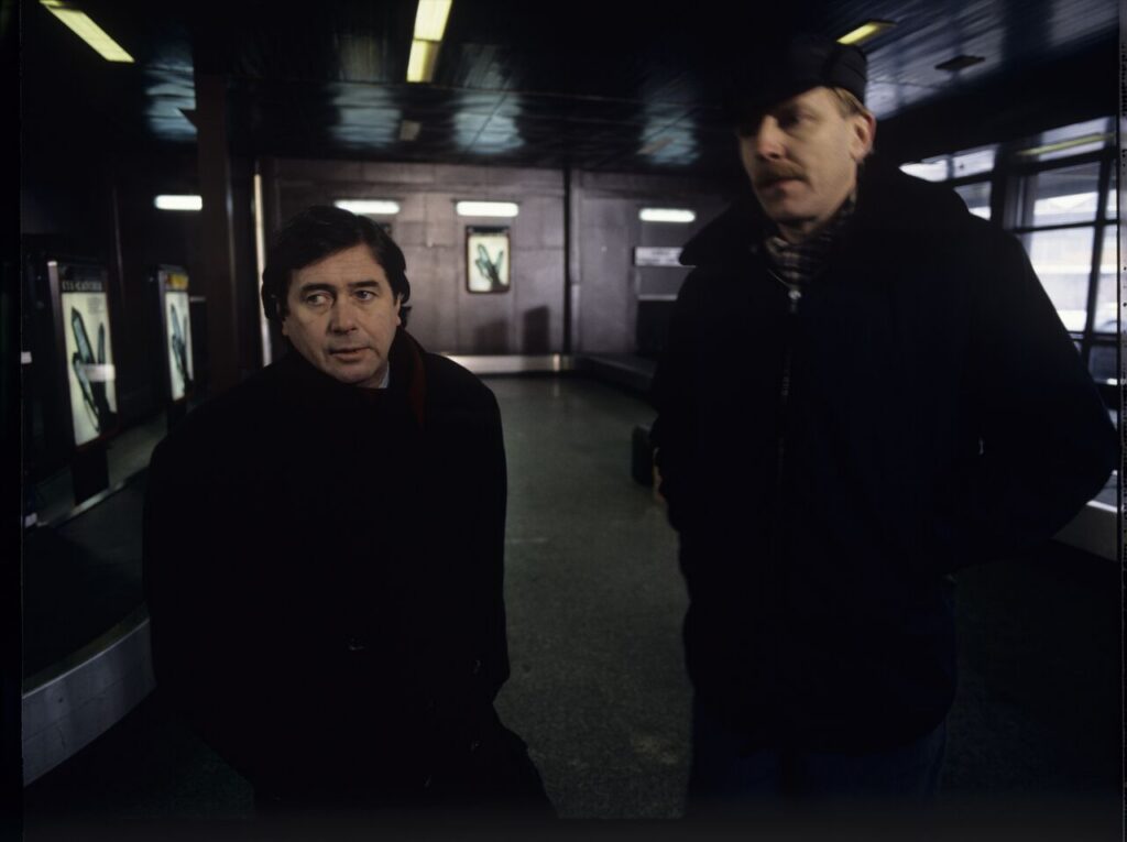 Mikołaj (Janusz Gajos) is waiting for his luggage in the arrivals hall at the Warsaw airport.