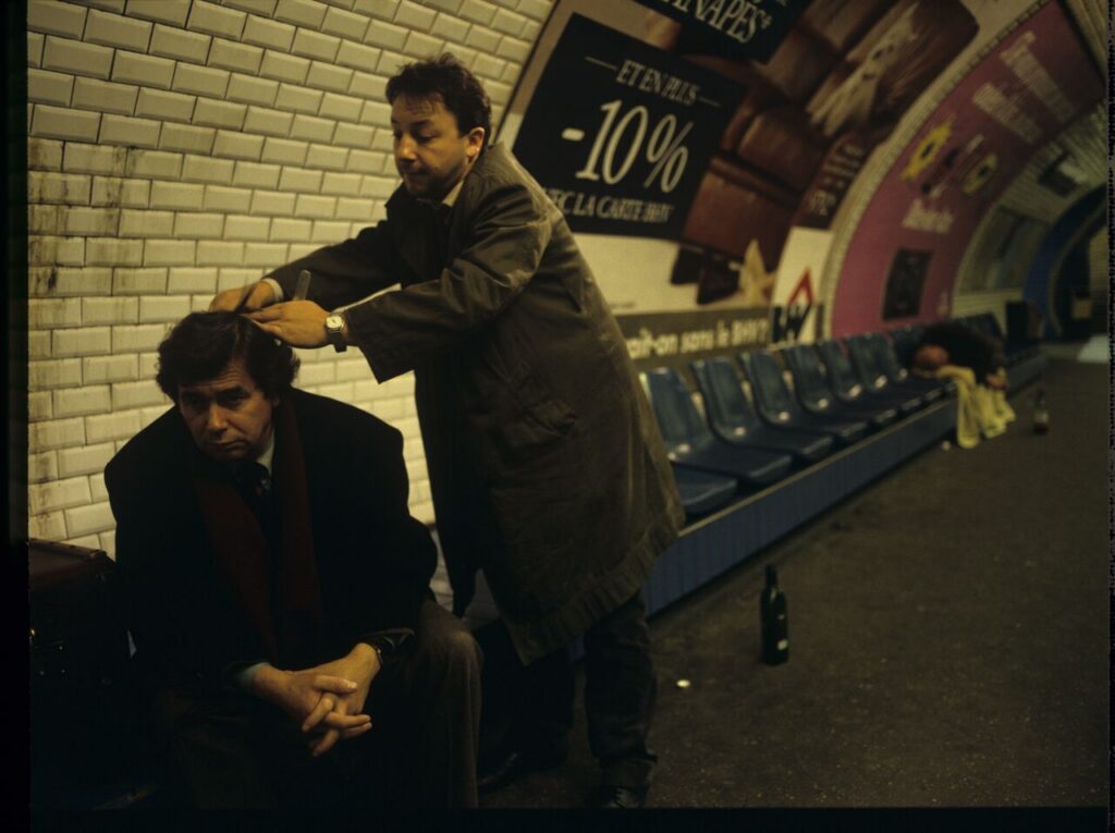 Hairdresser Karol (Zbigniew Zamachowski) cuts Mikołaj's (Janusz Gajos) hair in the basement of the Paris metro.