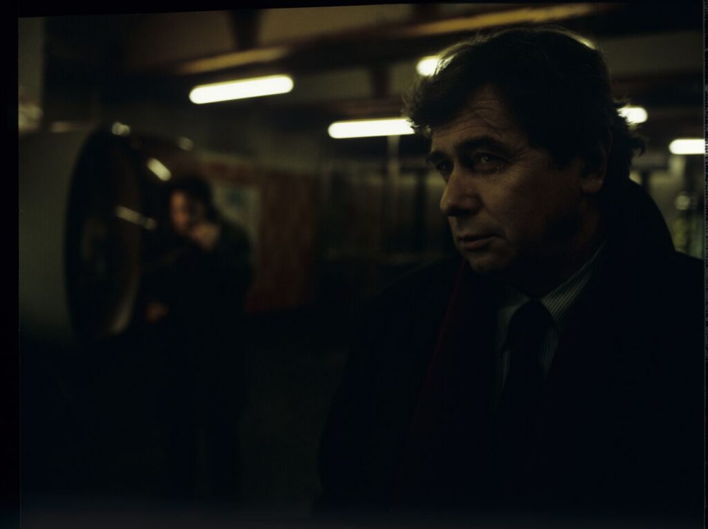 Mikołaj (Janusz Gajos) by the Paris metro. In the background Karol (Zbigniew Zamachowski) calls his wife Dominique.