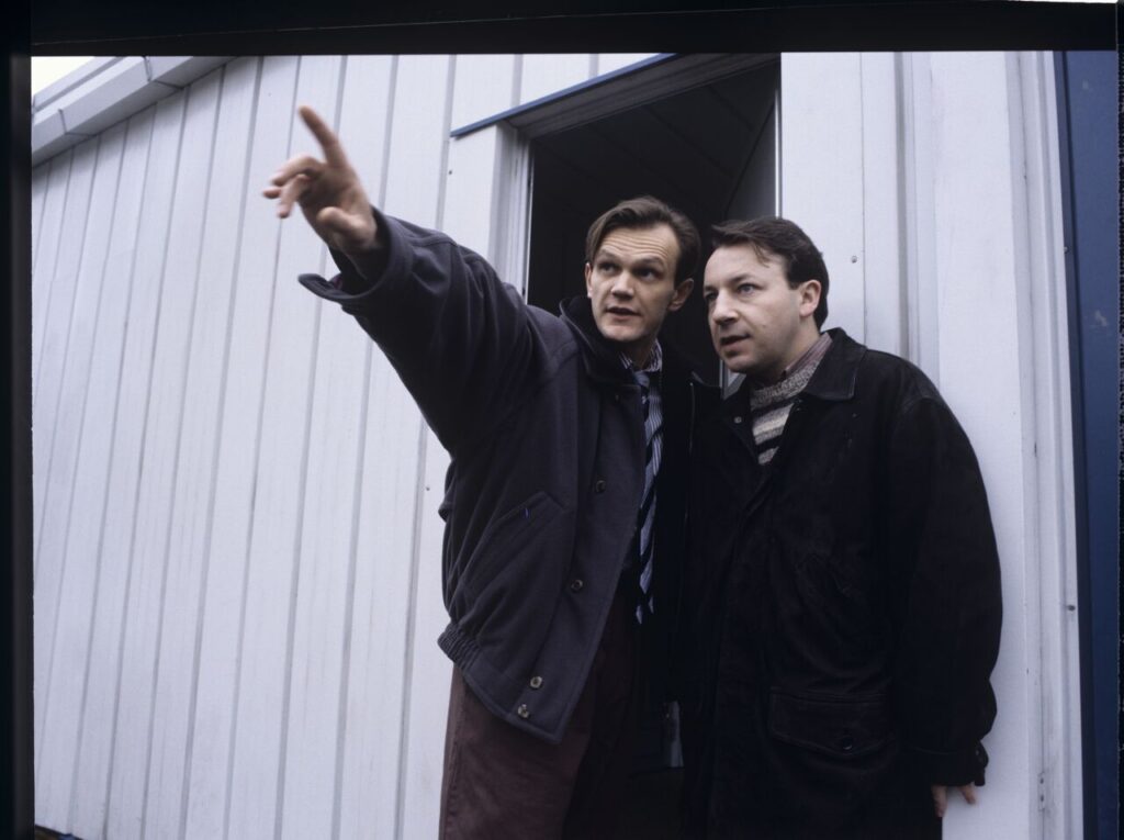 The owner of the currency exchange office (Pazura) shows Karol (Zamachowski) where to do his new job as a security guard.