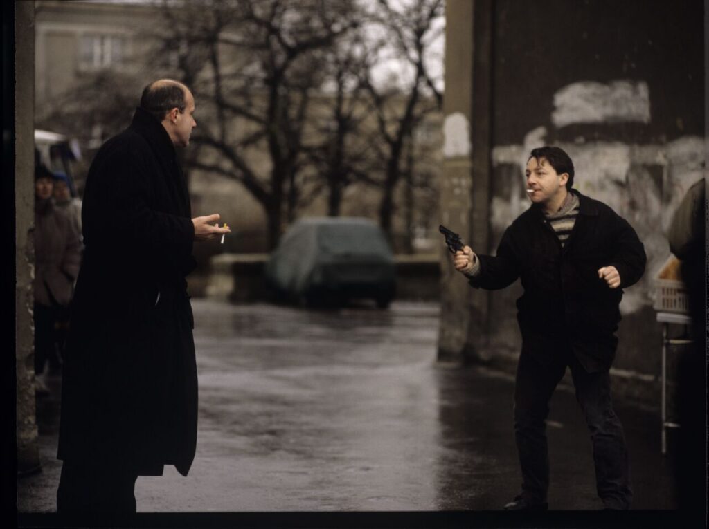 Karol (Zbigniew Zamachowski) and the "tall man" (Piotr Machalica) in front of the currency exchange office.