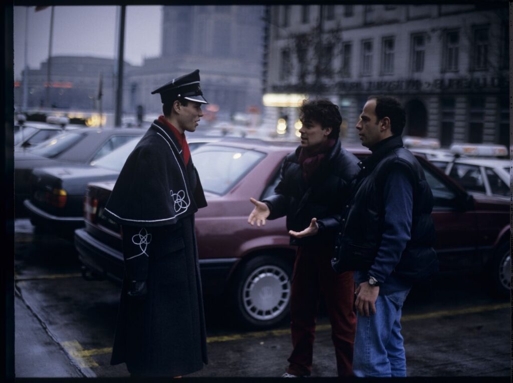 Passersby on a Warsaw street where Karol's car is parked.