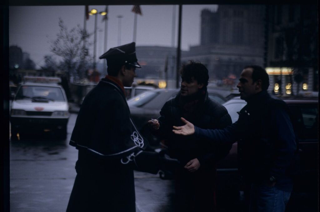 Passersby on a Warsaw street where Karol's car is parked.