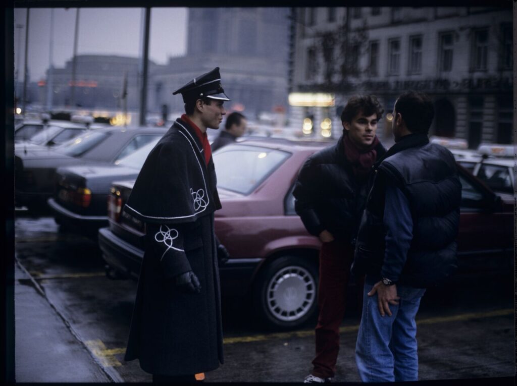 Passersby on a Warsaw street where Karol's car is parked.