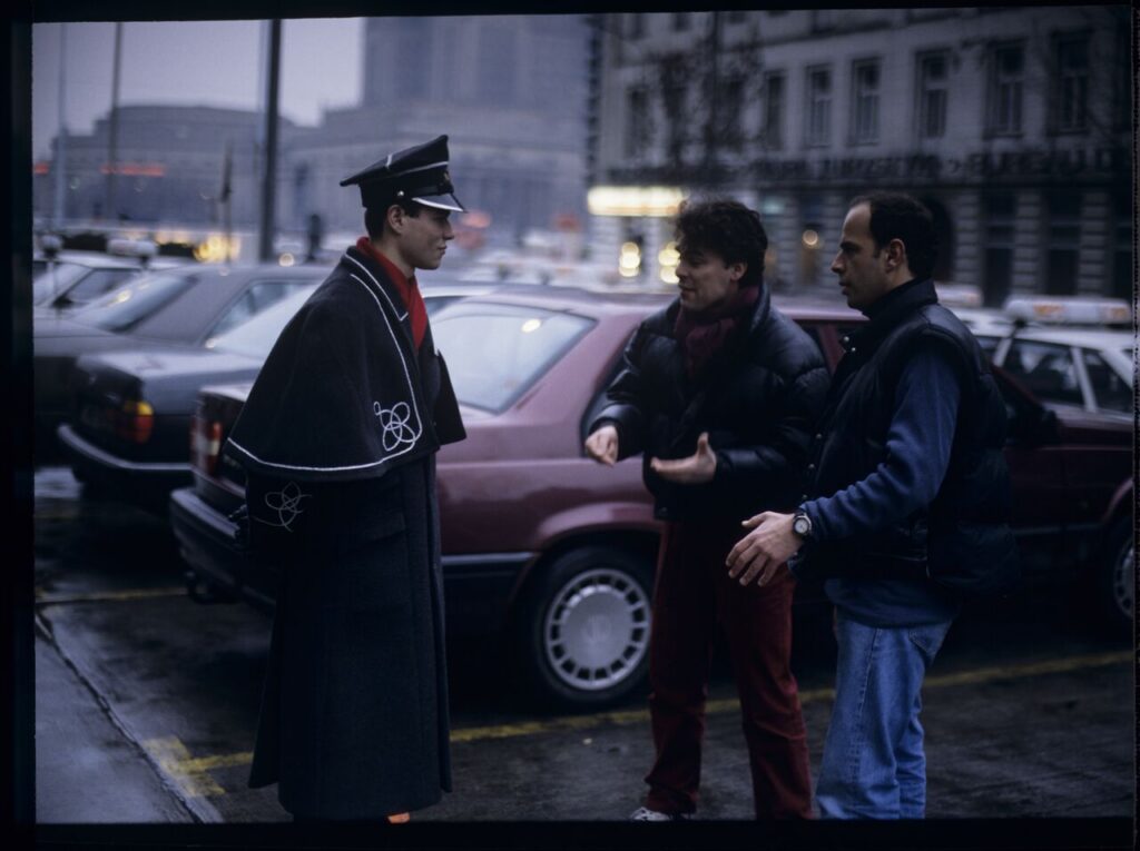Passersby on a Warsaw street where Karol's car is parked.