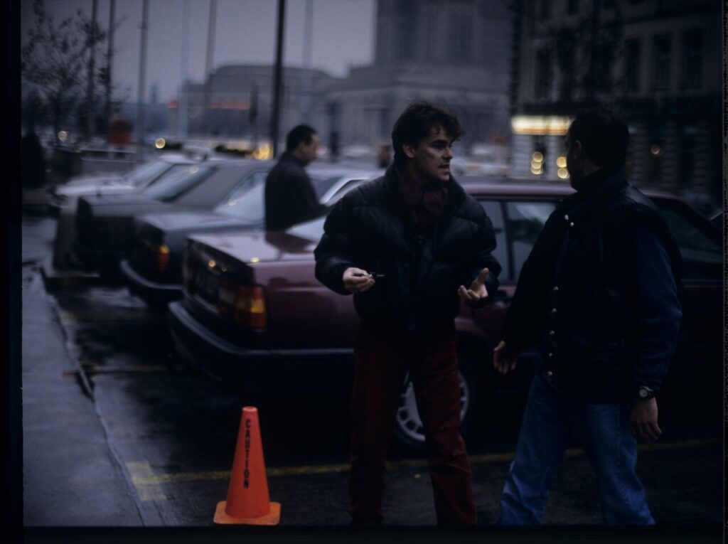 Passersby on a Warsaw street where Karol's car is parked.