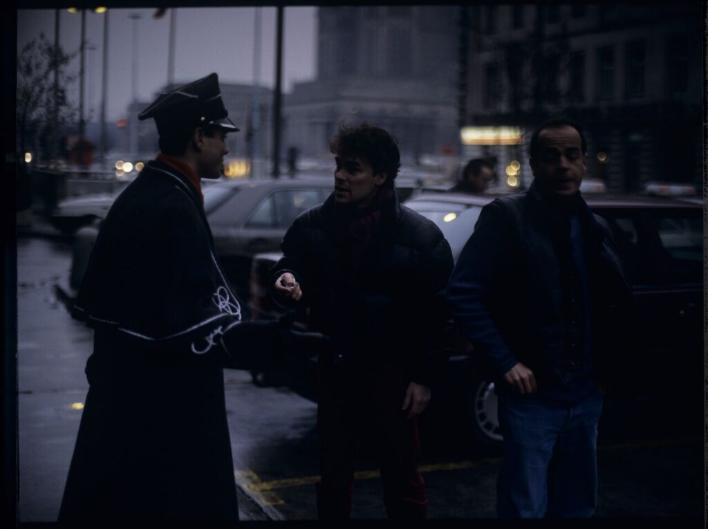 Passersby on a Warsaw street where Karol's car is parked.