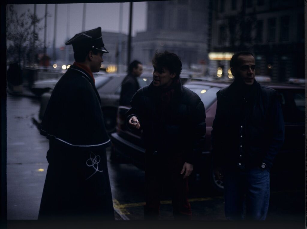 Passersby on a Warsaw street where Karol's car is parked.
