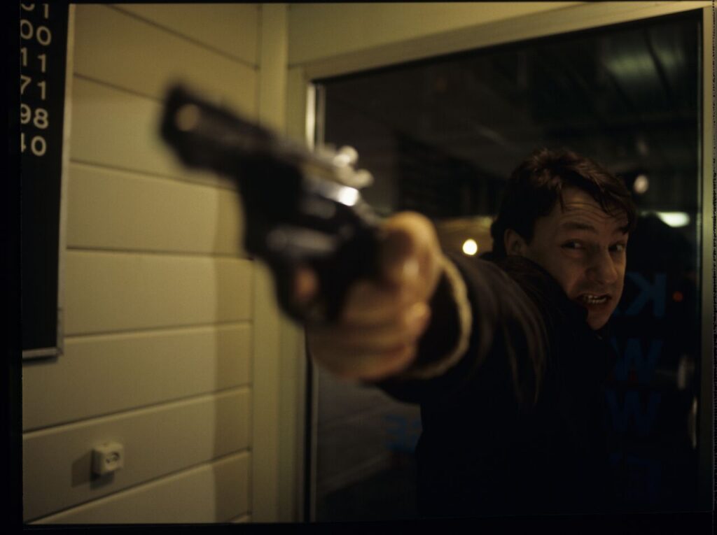 Karol (Zamachowski) as a security guard during a robbery at a currency exchange office. The scene did not appear in the film.