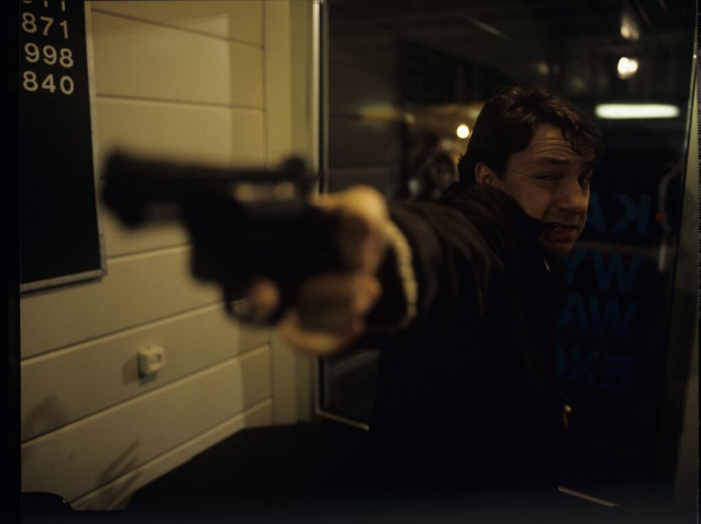 Karol (Zamachowski) as a security guard during a robbery at a currency exchange office. The scene did not appear in the film.