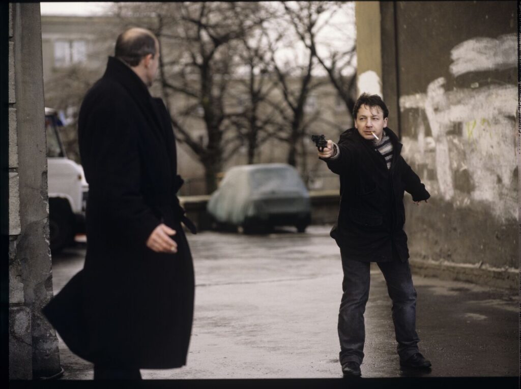 Karol (Zamachowski) distracts the attention of the man (Machalica) from the owner of the currency exchange office.