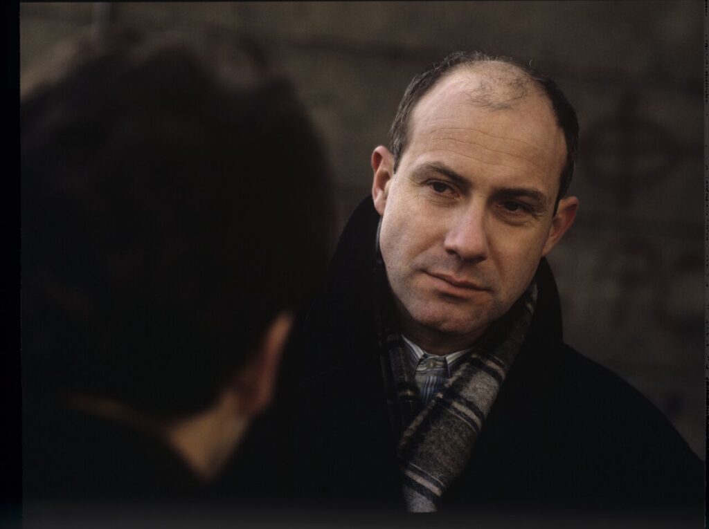 Karol (Zamachowski) distracts the attention of the man (Machalica) from the owner of the currency exchange office.