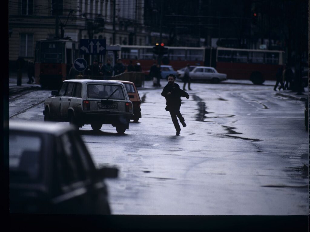 Karol (Zamachowski) tries to stop "Blondynka's" car to give her a message. The scene was not shown in the film.
