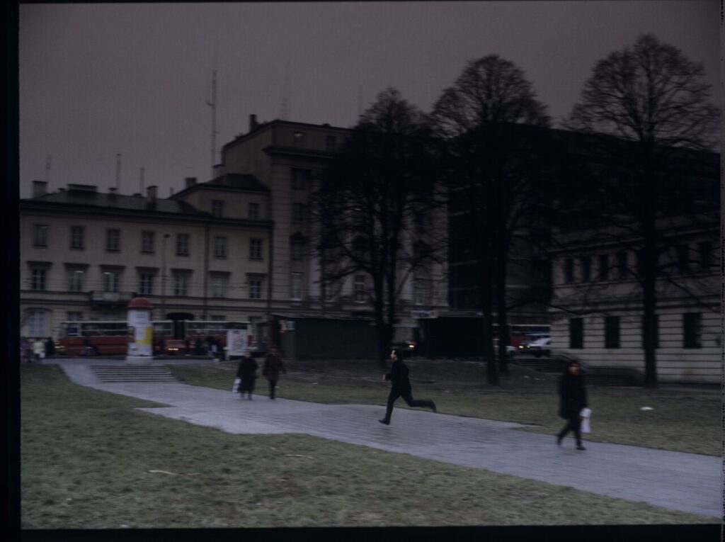 Karol (Zamachowski) tries to stop "Blondynka's" car to give her a message. The scene was not shown in the film.
