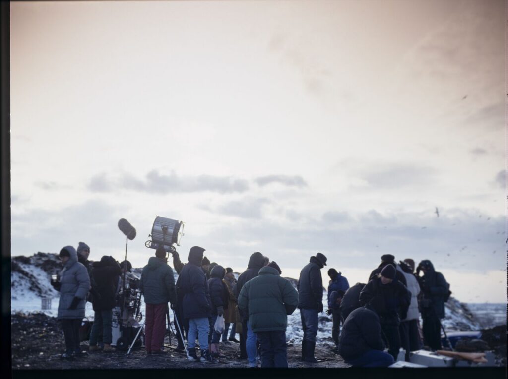 Krzysztof Kieślowski (director) surrounded by the crew on the set at a garbage dump.