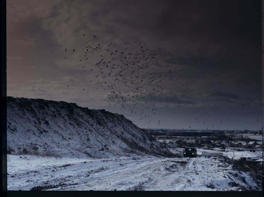 A scene at a garbage dump, where a car with a suitcase arrives in which Karol, the main character of the film, is locked.