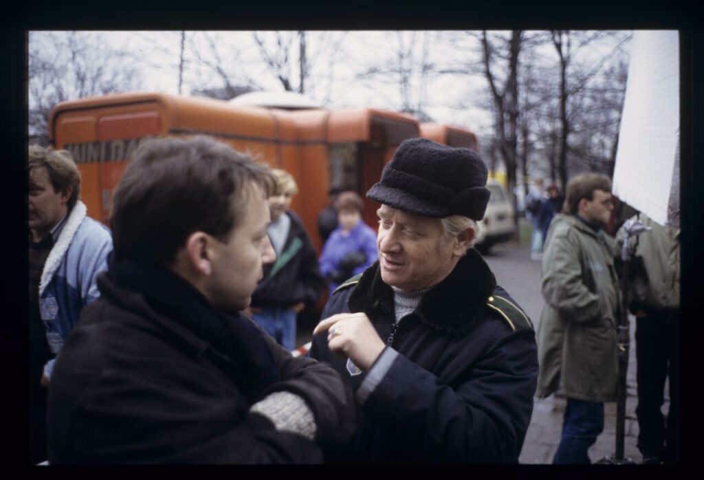 Zbigniew Zamachowski (playing Karol) surrounded by extras on the set in front of the currency exchange office.