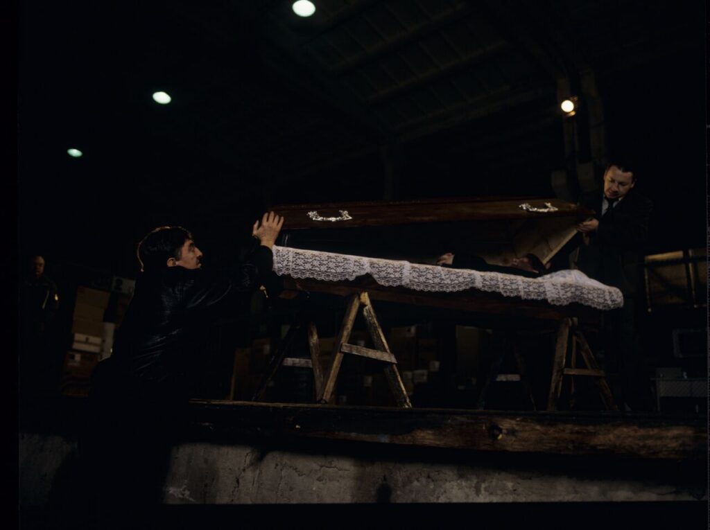 Karol (Zbigniew Zamachowski) and Mr. Bronek (Jerzy Trela) stand over the coffin of a "bought" corpse.