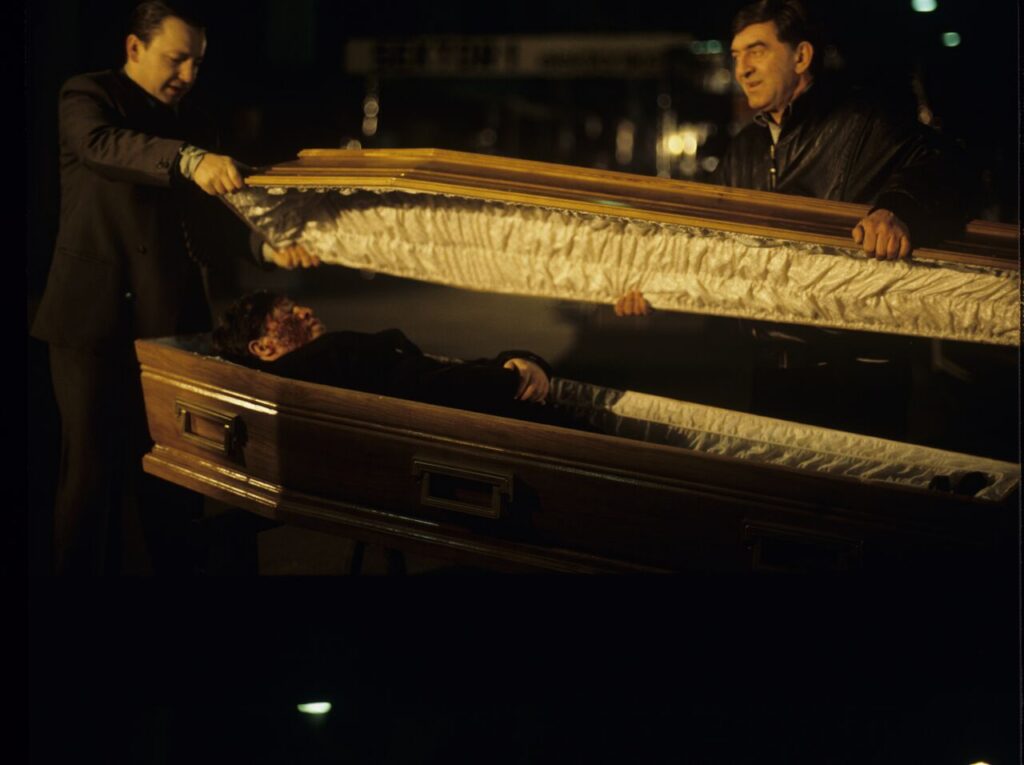 Karol (Zbigniew Zamachowski) and Mr. Bronek (Jerzy Trela) stand over the coffin of a "bought" corpse.