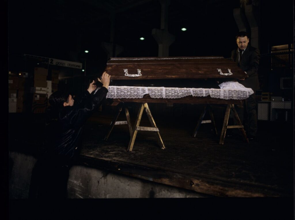 Karol (Zbigniew Zamachowski) and Mr. Bronek (Jerzy Trela) stand over the coffin of a "bought" corpse.