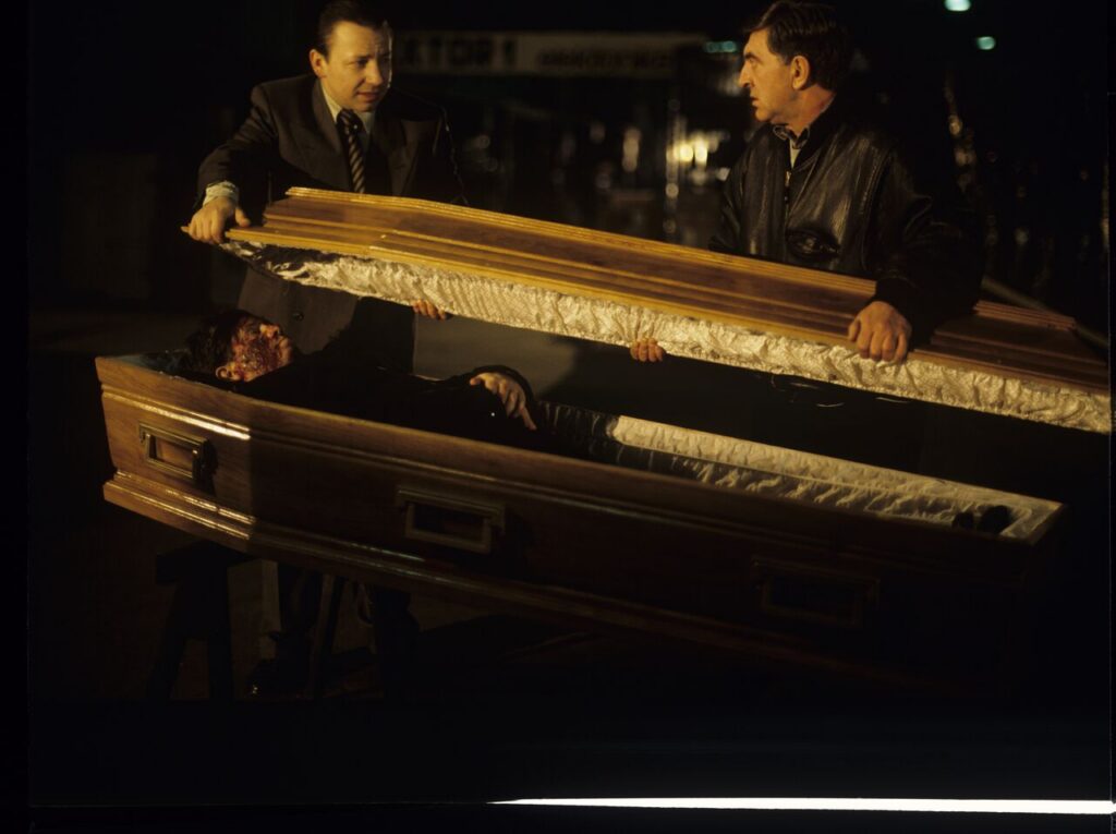Karol (Zbigniew Zamachowski) and Mr. Bronek (Jerzy Trela) stand over the coffin of a "bought" deceased.