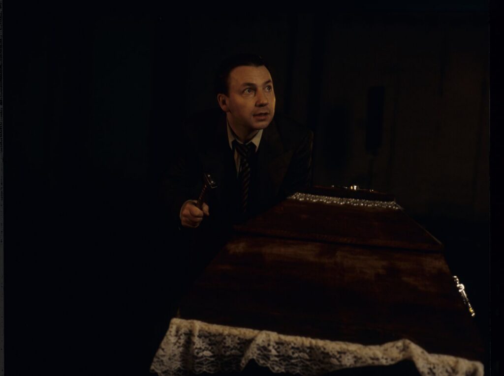 Karol (Zbigniew Zamachowski) stands over the coffin containing a "bought" corpse.