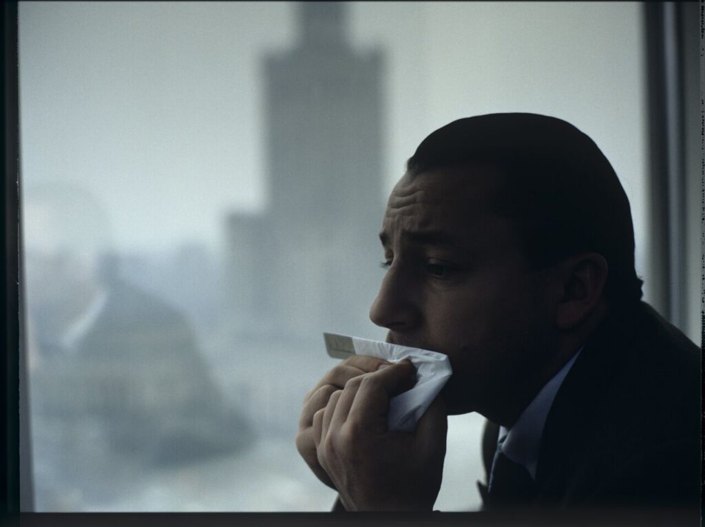 Karol (Zbigniew Zamachowski) plays a melody on a comb in his new office at the Marriott Hotel.