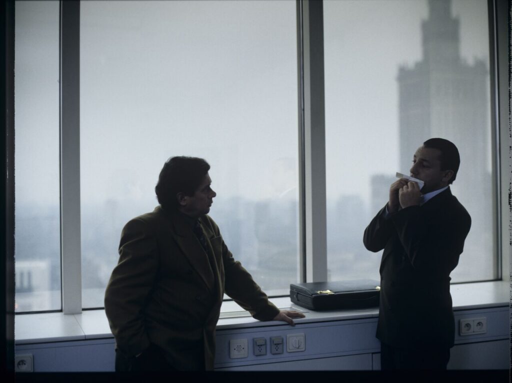 Karol (Zbigniew Zamachowski) plays a melody on a comb in his new office at the Marriott Hotel.