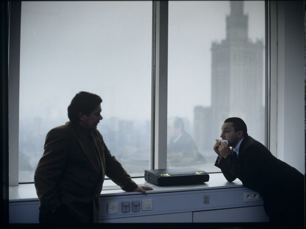 Karol (Zbigniew Zamachowski) plays a melody on a comb in his new office at the Marriott Hotel.