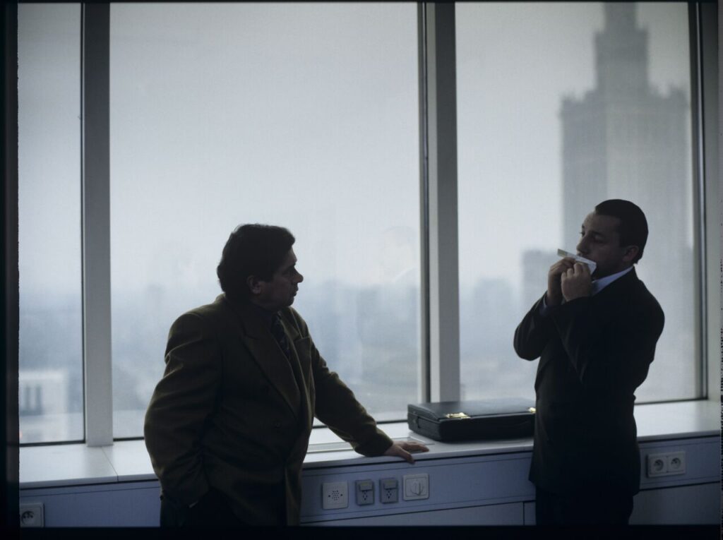 Karol (Zbigniew Zamachowski) plays a melody on a comb in his new office at the Marriott Hotel.