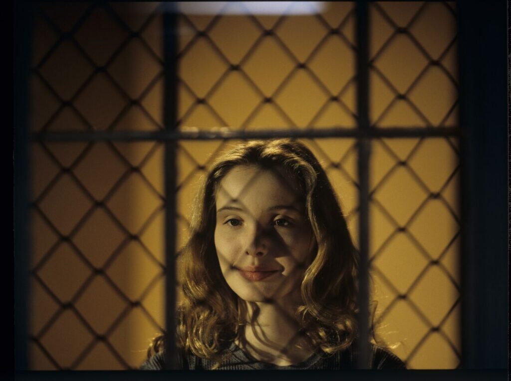 Dominique (Julie Delpy) in the barred prison window, where he is serving his sentence for the murder of her husband.