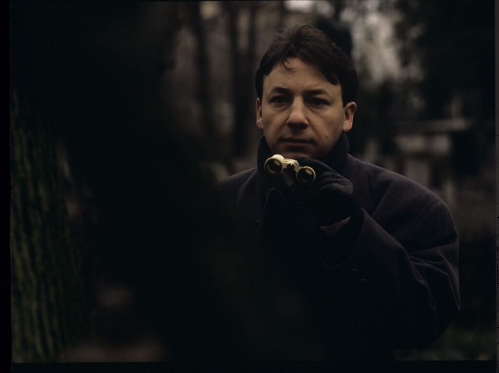 Karol (Zbigniew Zamachowski) observes his own funeral through binoculars.