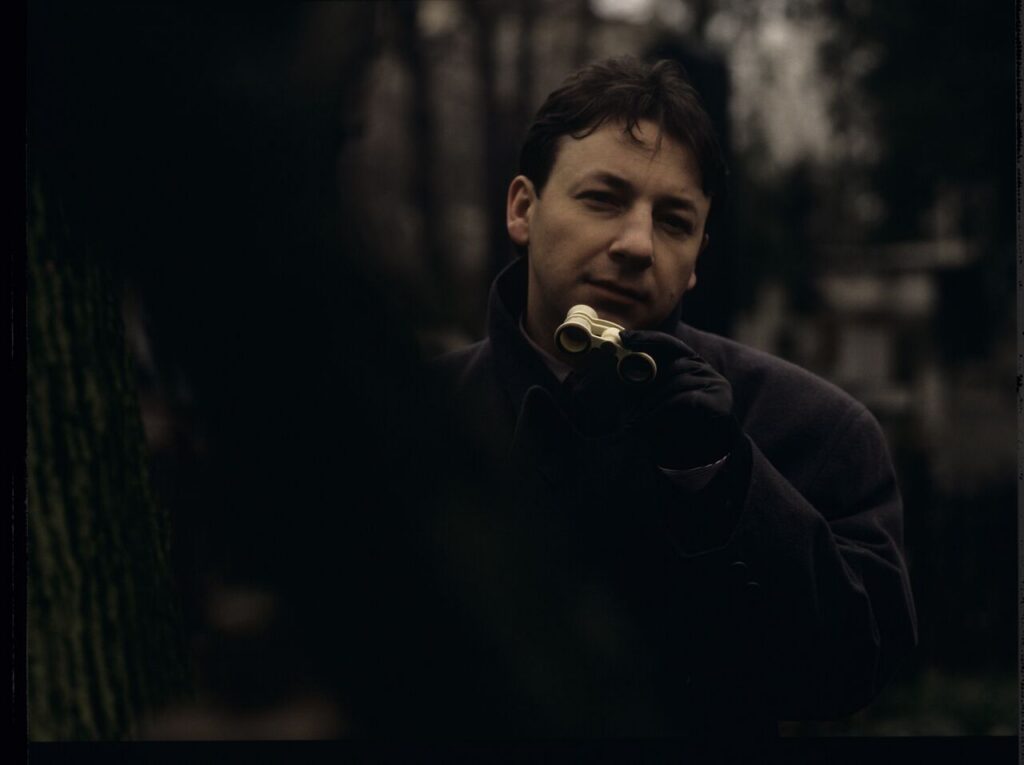 Karol (Zbigniew Zamachowski) observes his own funeral through binoculars.