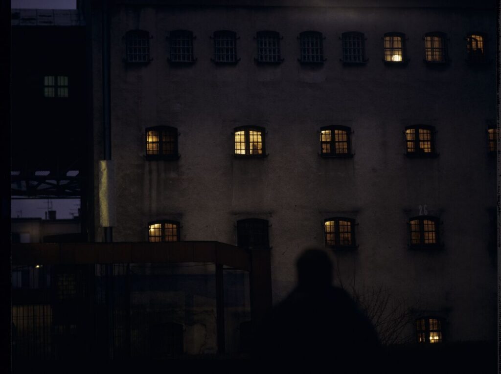 Karol (Zbigniew Zamachowski) in front of the prison building. In the window we can see the silhouette of his wife.